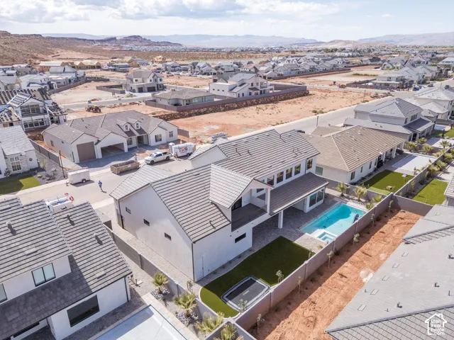 Modern exterior featuring a covered patio, integrated pool, paver hardscaping, and artificial turf