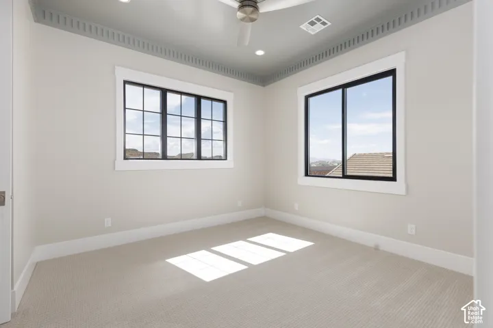 Carpeted flooring, two large windows with black frames, detailed crown molding, recessed lighting, and a ceiling fan