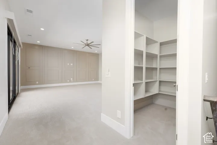 Built-in shelving, recessed lighting, ceiling fan, accent paneling, and wide baseboards