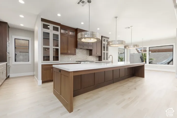 Expansive kitchen island with a light-toned countertop, wood-finish flooring, recessed lighting, and large windows