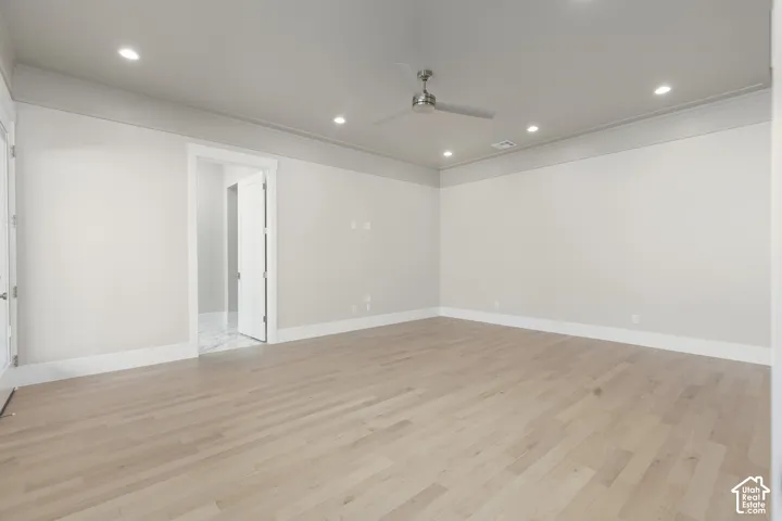 Light wood-finish flooring, recessed lighting, ceiling fan, crown molding, and white trim throughout