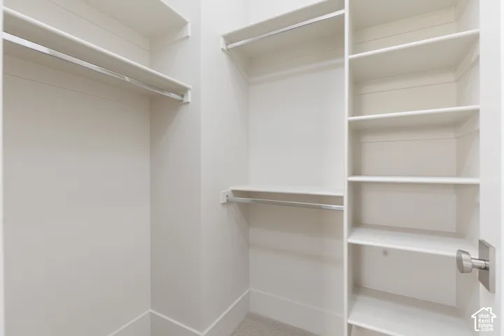 Built-in closet system featuring multiple hanging rods, extensive shelving, and neutral wall tones