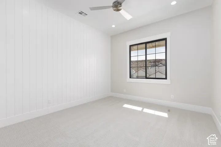 Carpeted room featuring a ceiling fan, recessed lighting, a window with black framing, and a shiplap accent wall