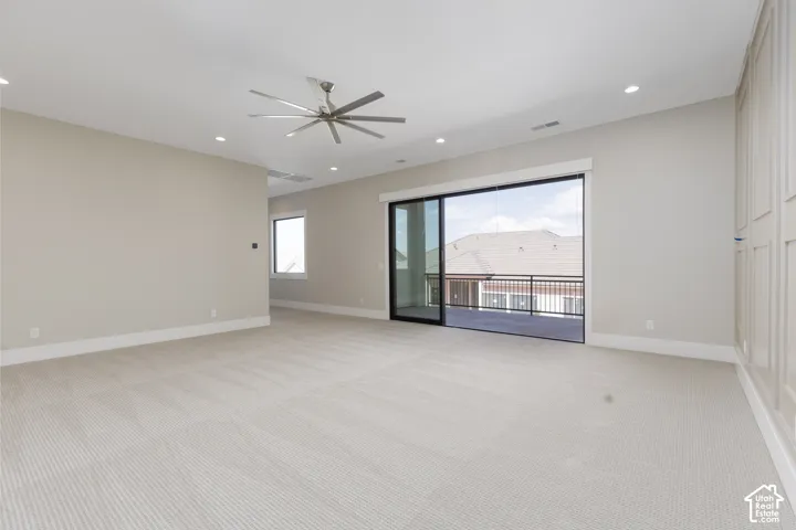 Recessed lighting, ceiling fan, sliding glass door, private balcony with metal railing, panel accent wall