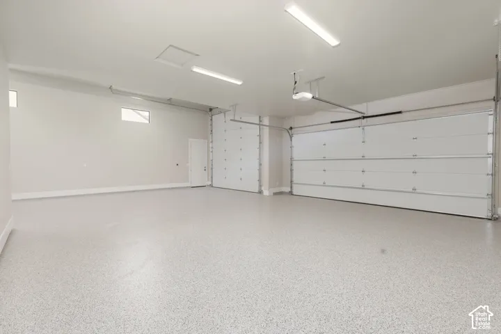 Spacious garage with two overhead doors, epoxy flooring, and ample overhead lighting