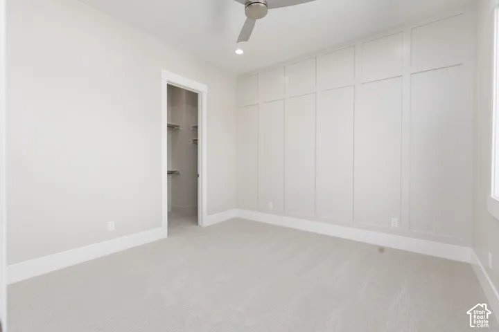 Recessed lighting, ceiling fan, plush carpet flooring, built-in wall paneling, and a walk-in closet with shelving