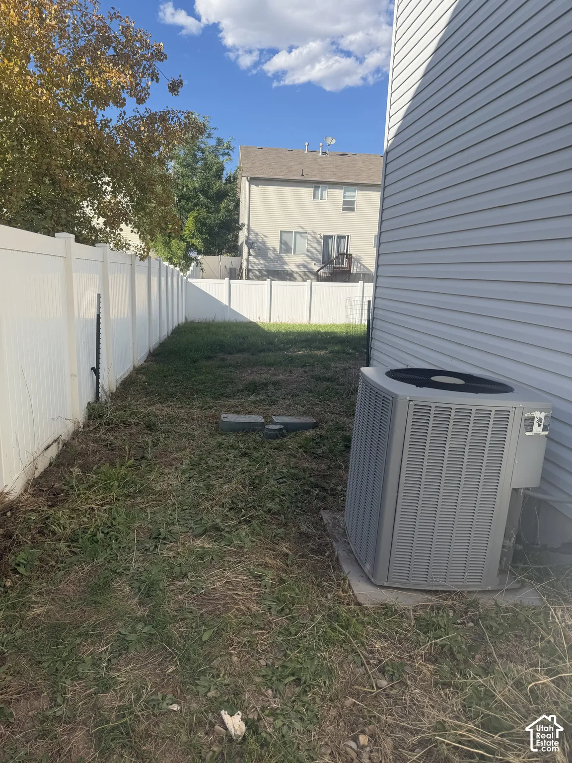 Rear exterior featuring vinyl siding, a full-height privacy fence, and an air conditioning unit