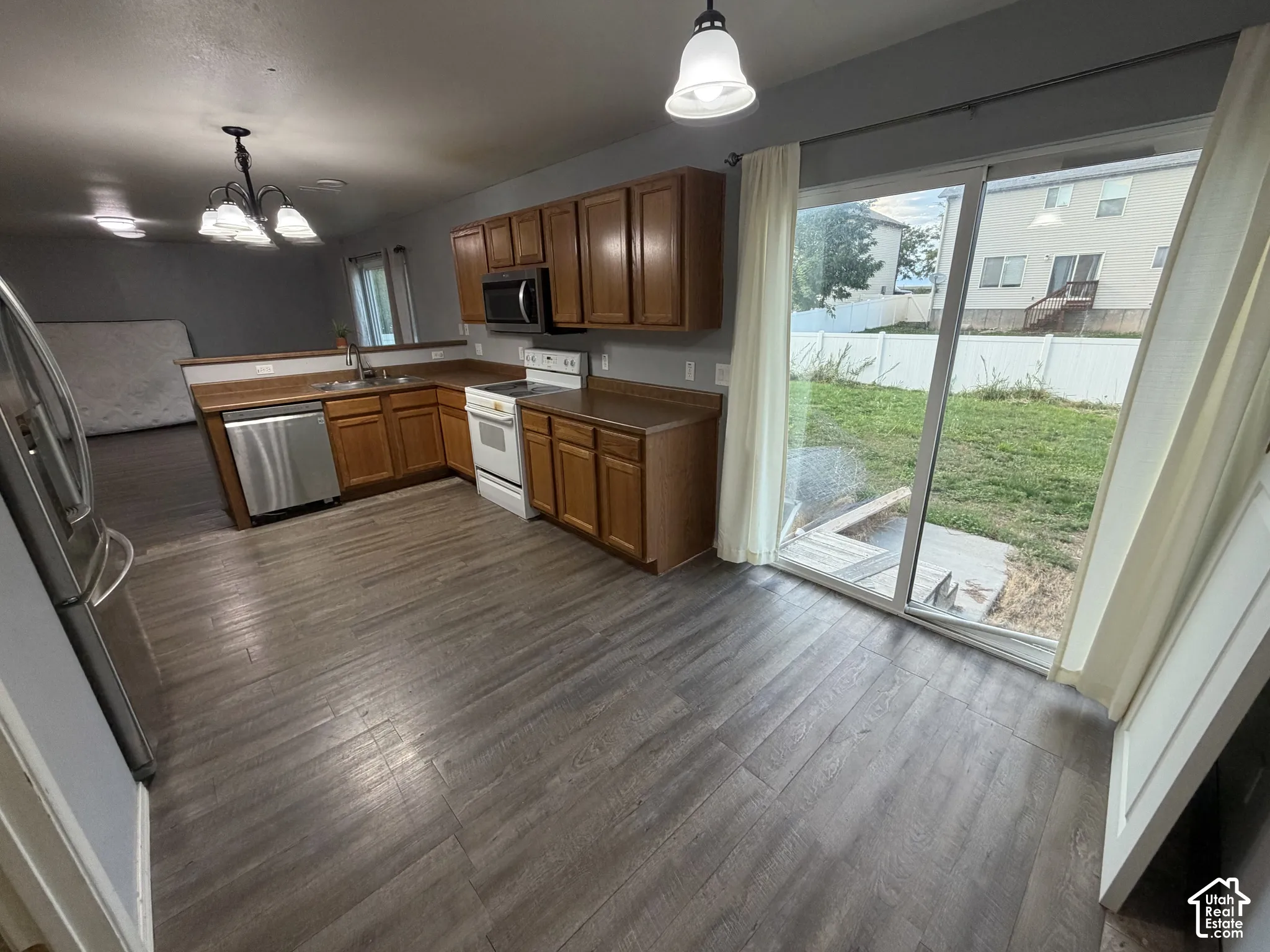 Kitchen featuring wood-finish flooring, wood cabinetry, stainless steel dishwasher, and a built-in microwave