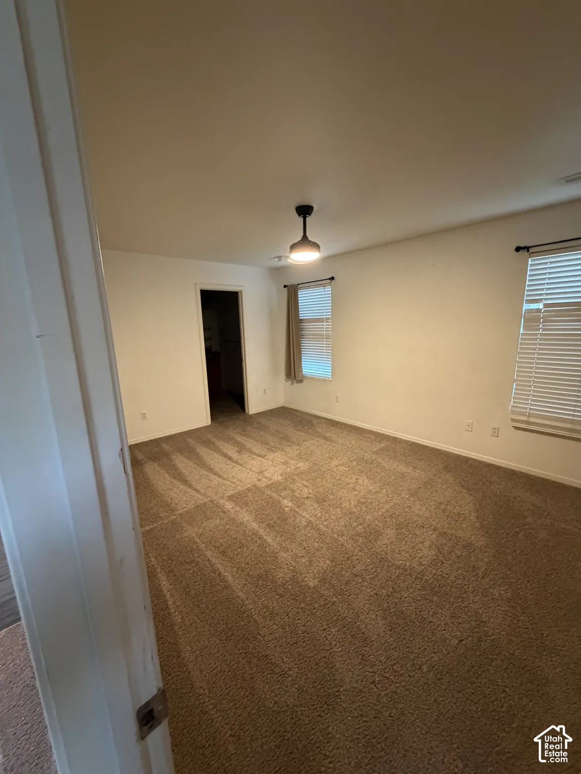 Spacious room featuring neutral carpet flooring and white walls
