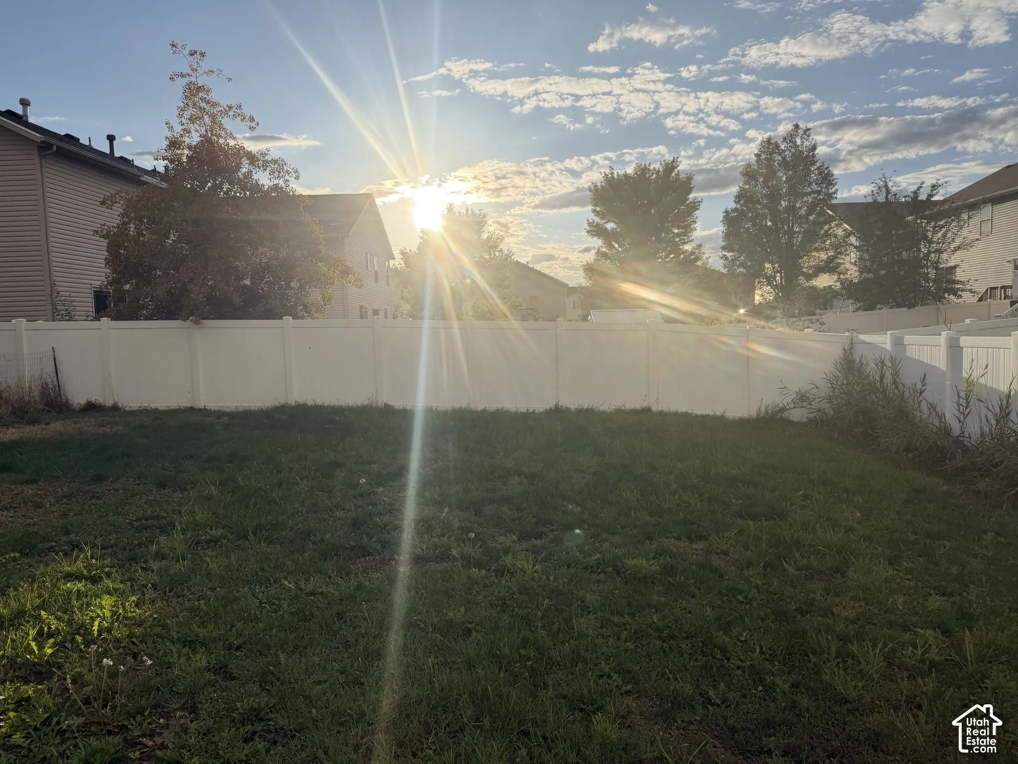 Expansive yard area featuring a white privacy fence