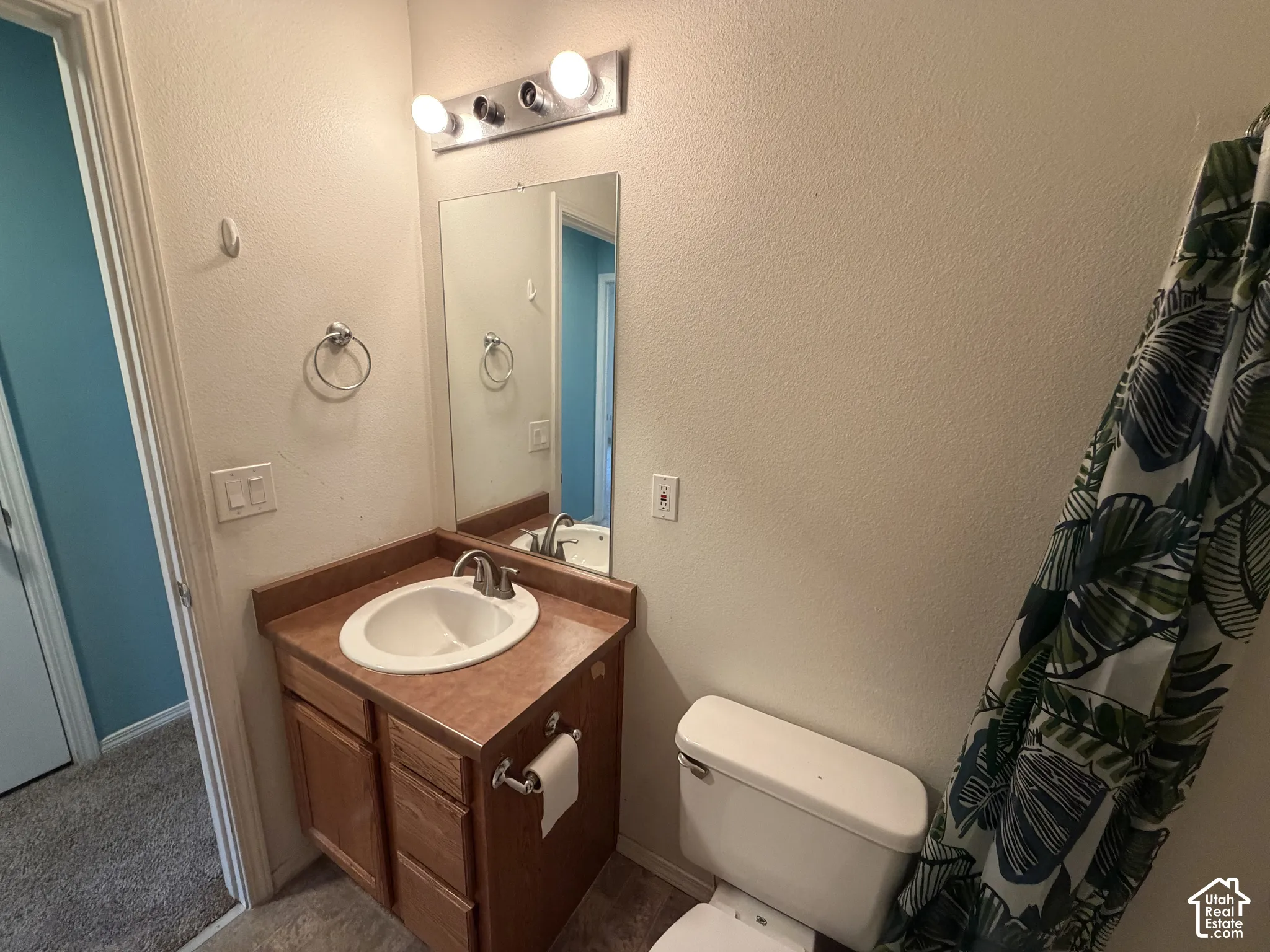 Bathroom featuring a wood-finish vanity with an integrated sink, a wall-mounted mirror, and overhead vanity lighting