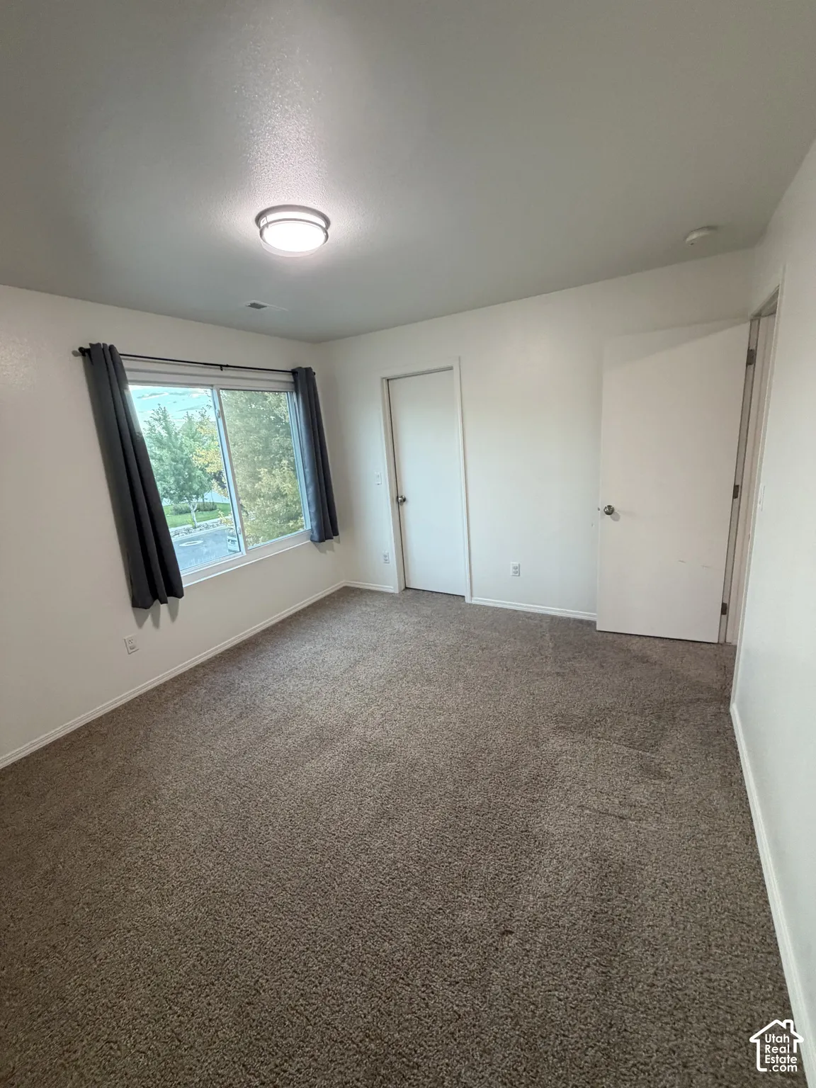 Neutral-toned carpeting, white walls, and a contemporary ceiling light fixture