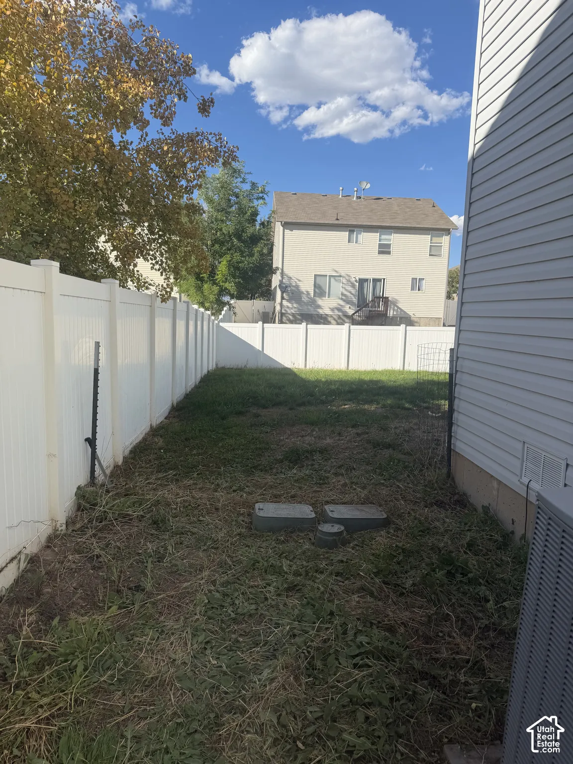 Enclosed backyard featuring a white privacy fence.