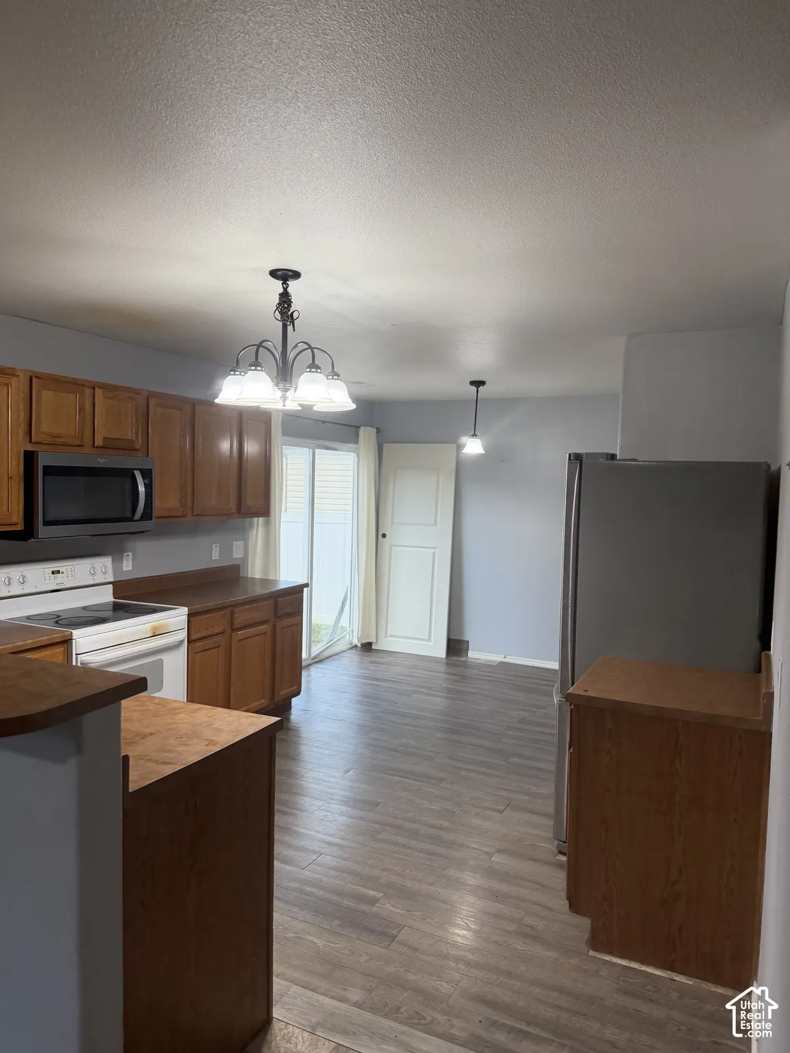 Kitchen featuring wood-finish flooring, wood-finish cabinetry, and stainless steel appliances