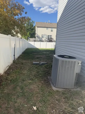 Rear exterior featuring vinyl siding, a full-height privacy fence, and an air conditioning unit