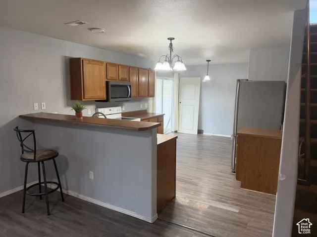Open-concept kitchen with wood-finish flooring, wood cabinetry, and a breakfast bar