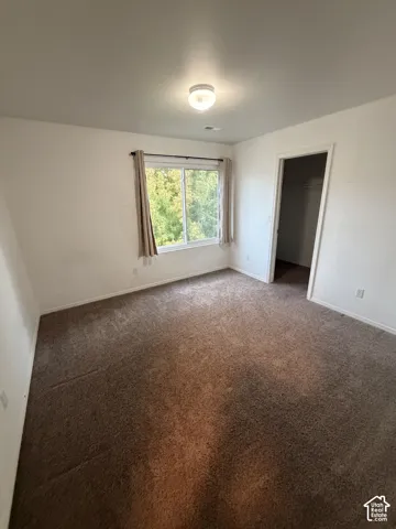 Carpeted flooring, white walls, ceiling-mounted light fixture, and a window with a natural scenery backdrop