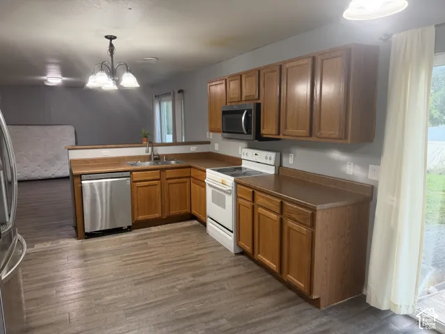 Kitchen featuring wood-finish flooring, wood cabinetry, stainless steel dishwasher, and a built-in microwave