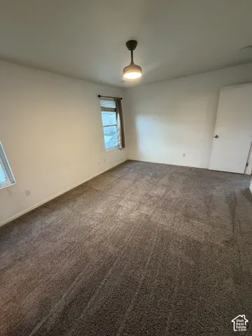 Neutral tone wall paint, textured carpet flooring, window with blinds, and a flush-mount ceiling light fixture