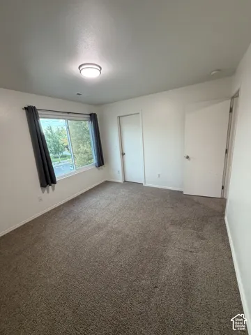 Neutral-toned carpeting, white walls, and a contemporary ceiling light fixture