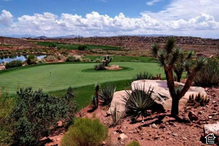 Expansive golf course green with a water feature, desert landscaping, and distant mountain scenery