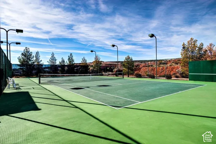 Outdoor tennis court featuring a hard surface, perimeter fencing, and integrated lighting