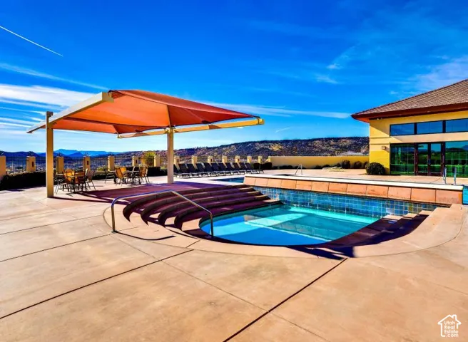 Expansive concrete pool deck featuring a swimming pool, integrated steps, and handrails