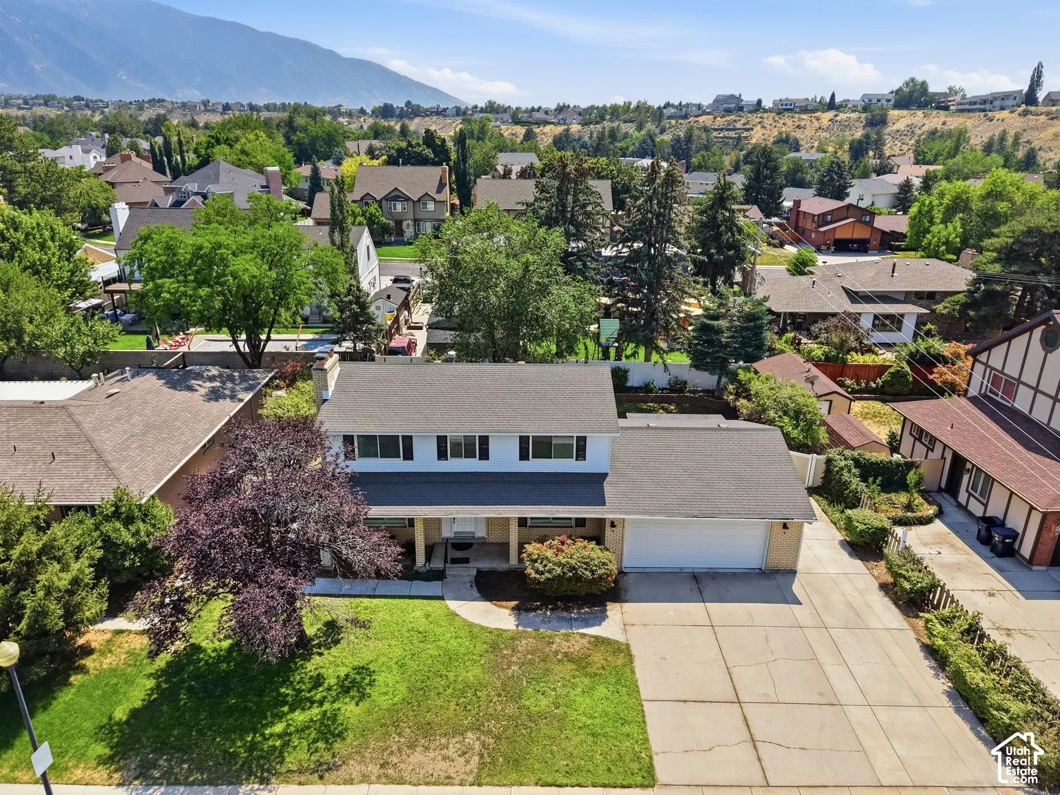 Traditional two-story residence with a two-car garage, mature landscaping, and a paved driveway