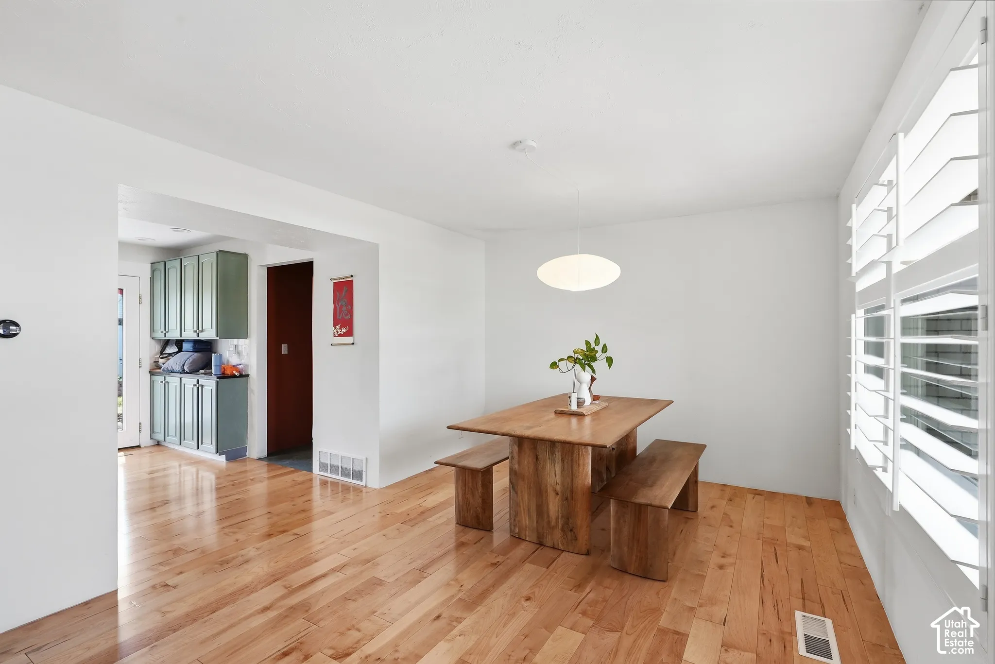 Hardwood flooring, crisp white walls, contemporary pendant lighting, and built-in window shutters