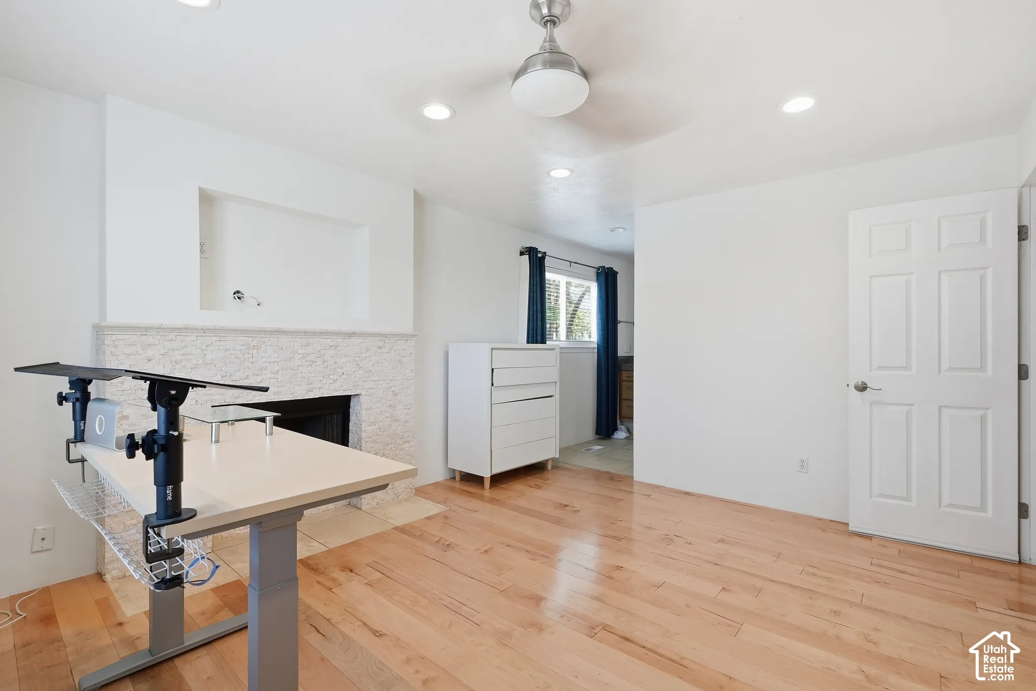 Hardwood flooring and recessed lighting illuminate this interior space, featuring a built-in fireplace with a stone surround and an integrated media niche