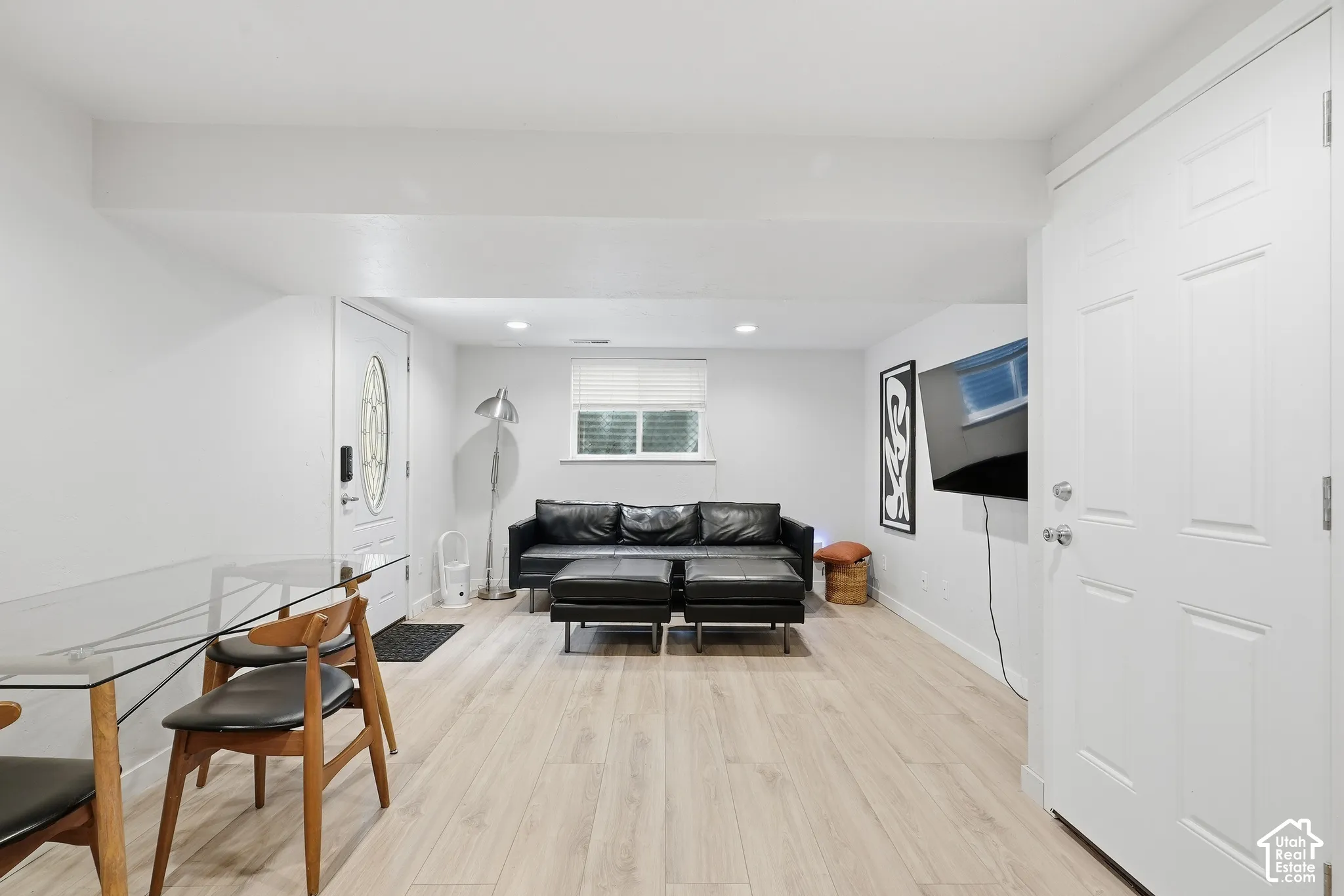 Light wood-finish flooring, white walls, recessed lighting, and a white paneled door