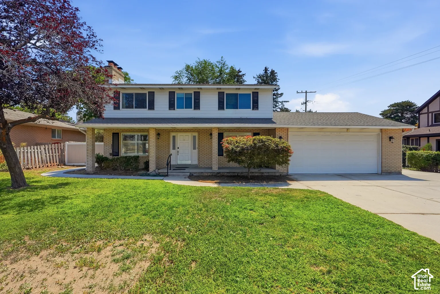 Two-story residence featuring light brick and siding exterior, an attached two-car garage, and a covered front porch