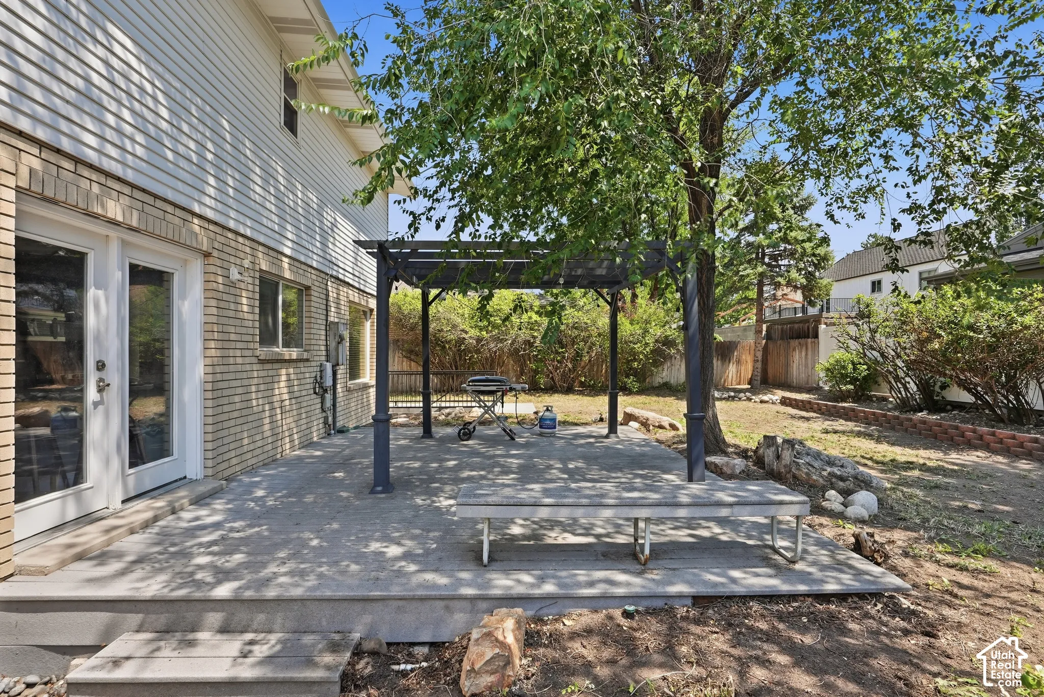 Expansive patio area with a dark metal pergola, providing an outdoor living extension