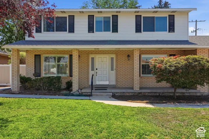 Brick facade with white siding, covered front porch, and black window shutters