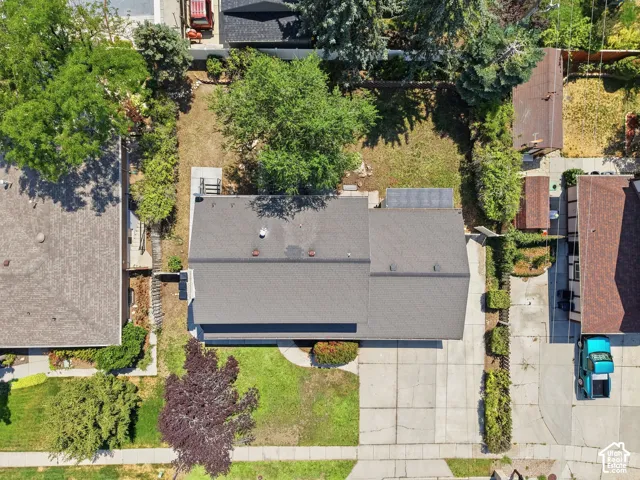 Expansive paved driveway, mature landscaping, and an asphalt shingle roof