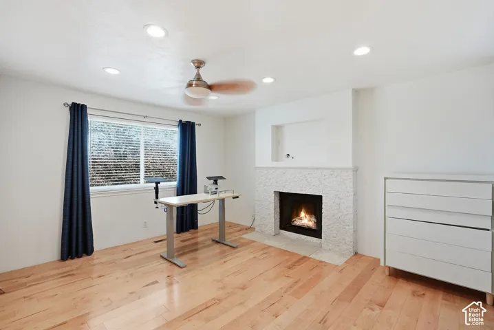 Wood-finish flooring, recessed lighting, and a textured fireplace with a mantel