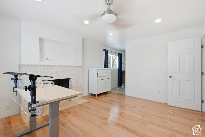 Hardwood flooring and recessed lighting illuminate this interior space, featuring a built-in fireplace with a stone surround and an integrated media niche