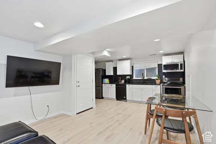 Kitchenette featuring white cabinetry, black countertops, and a subway tile backsplash