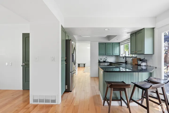 Kitchen featuring wood-finish flooring, dark stone countertops, beadboard island detailing, shaker-style cabinetry, and stainless steel appliances