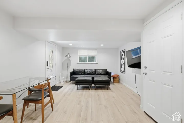 Light wood-finish flooring, white walls, recessed lighting, and a white paneled door