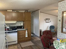 Kitchen with wood-finish cabinetry, white built-in appliances, and wood-finish flooring