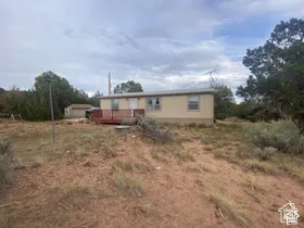Single-story residence with a tan exterior, front deck, and a small outbuilding