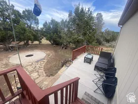 Outdoor deck with red-stained railings, concrete surface, and a stone-paved fire pit area