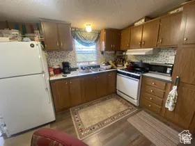Wood-finish flooring, wood cabinetry, built-in range, and a dual basin sink
