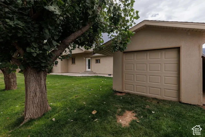 Exterior stucco finish, work shop/storage with overhead door, and established trees