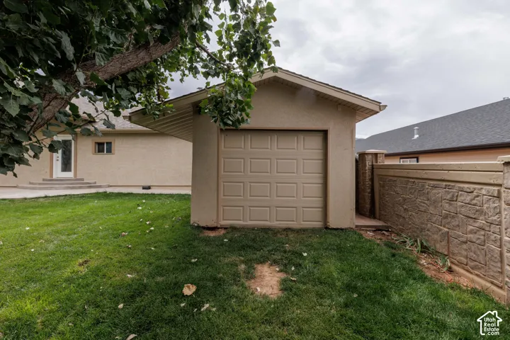 Detached workshop/storage with an overhead door, stucco exterior, and sloped roof