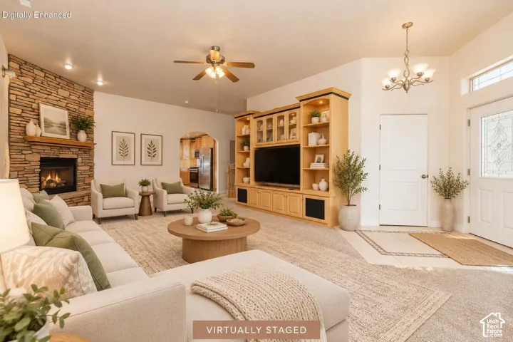 Stacked stone fireplace, built-in entertainment center, vaulted ceiling with ceiling fan, decorative entry door with leaded glass, and tiled entryway flooring