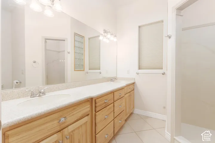 Primary bathroom with dual vanity with wood-finish cabinetry, integrated sinks, and polished chrome fixtures