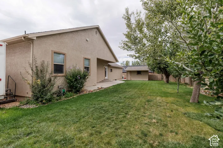 Expansive lawn, mature trees, stucco exterior, and a detached shed structure
