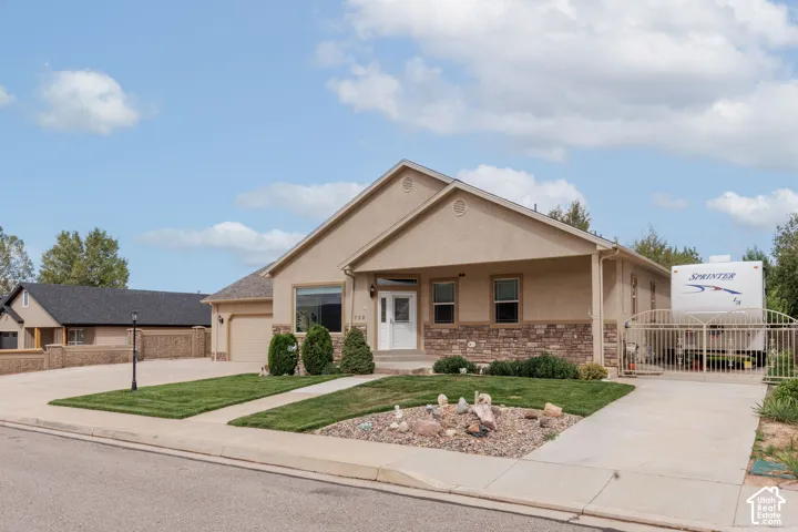 Stucco exterior with stone accent, covered entryway, and an attached garage with RV parking on both sides